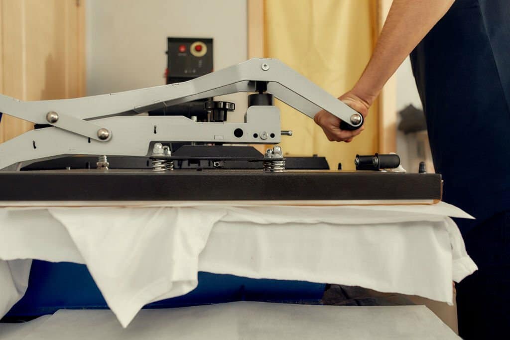 male worker using heat press transfer machine for printing t-shirt